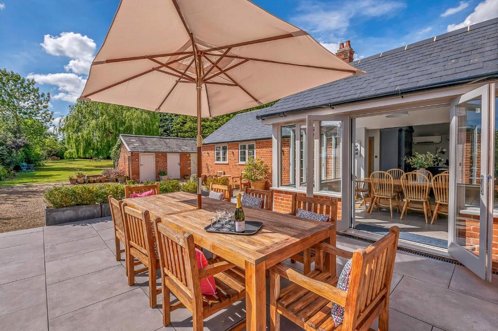 una mesa de madera con una sombrilla en el patio en 'The School House' - Luxury Home with Large Garden en Long Melford