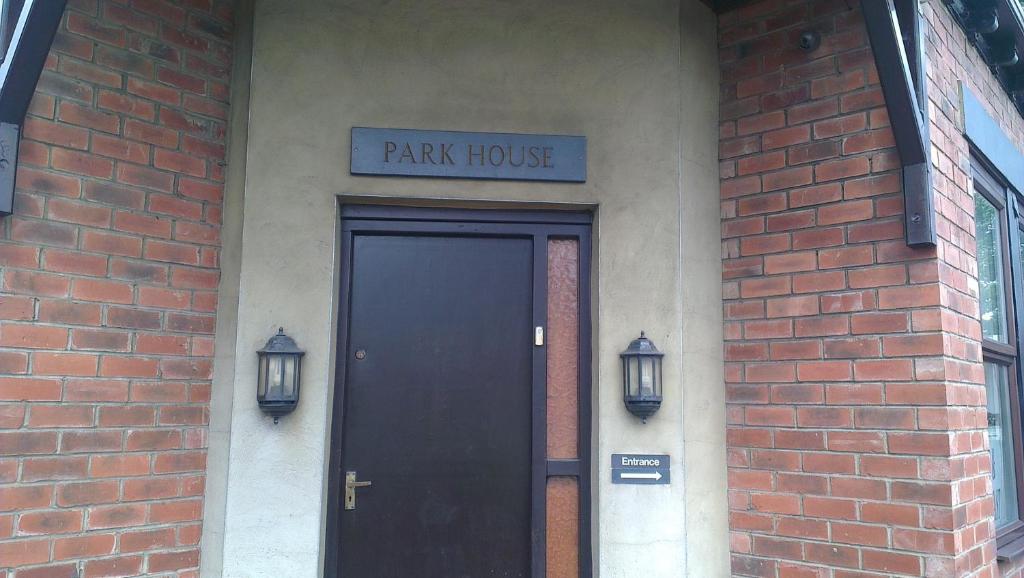 un edificio de ladrillo con una puerta negra y un cartel de la casa del parque en Park House B&B, en Leeds