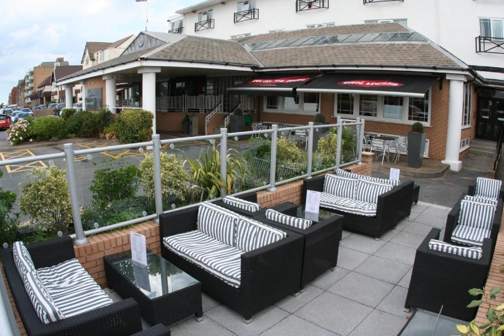 a patio area with chairs, tables and umbrellas at Inn On The Prom At The Fernlea Hotel in Lytham St Annes