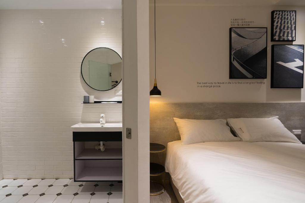 a bedroom with a bed and a mirror and a sink at The Way Inn in Taichung