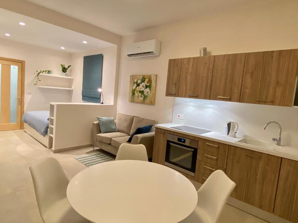 eine Küche und ein Wohnzimmer mit einem weißen Tisch und Stühlen in der Unterkunft Mosta Garden Studio in Mosta