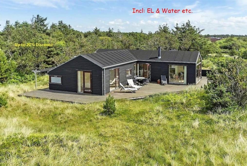 uma casa negra no meio de um campo em Luxury 109m2 cottage DunesNorthSea LøkkenBlokhus Denmark em Lokken