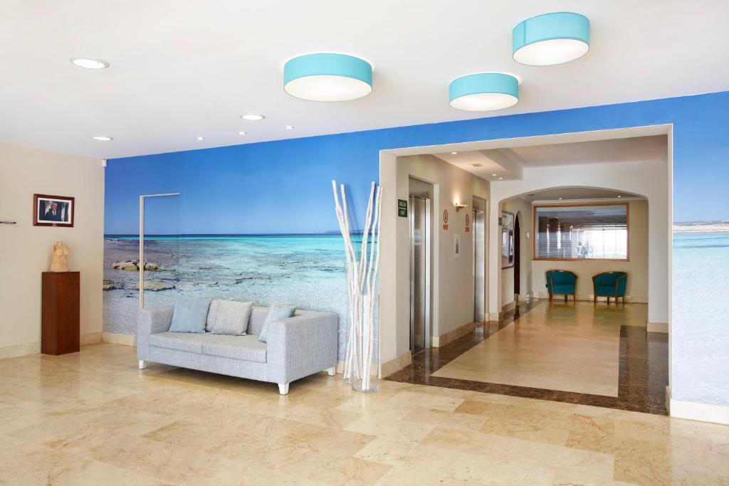 a living room with a couch and a blue wall at Universal Hotel Marqués in Colònia de Sant Jordi