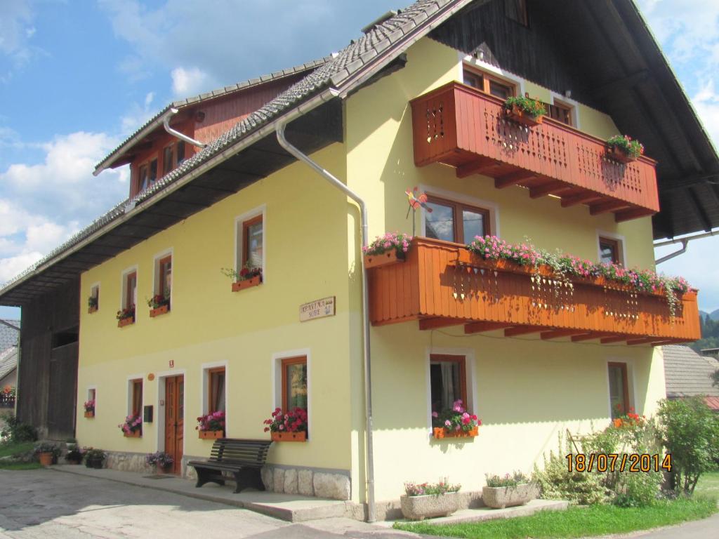 a yellow building with balconies and flowers on it at Apartments and Rooms Hodnik Slavko in Bohinj