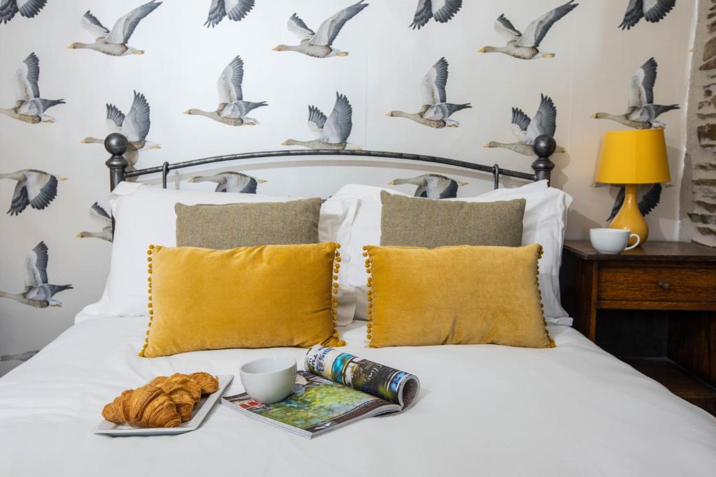 a bed with a tray of croissants and birds on the wall at The Olde Malthouse Inn in Tintagel