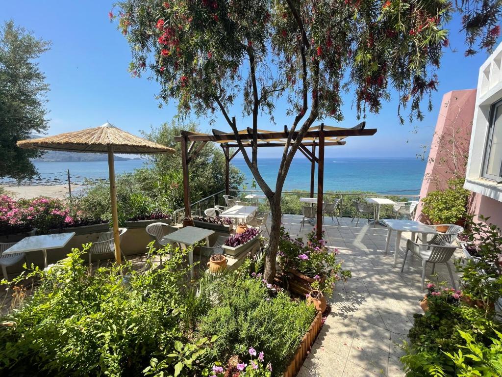a patio with tables and chairs and the ocean at Horizon Beach Hotel in Plakias