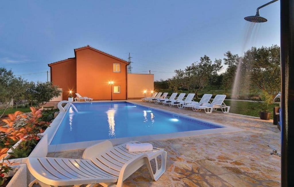 a swimming pool with lounge chairs next to a house at Villa Jelena in Kastel Novi
