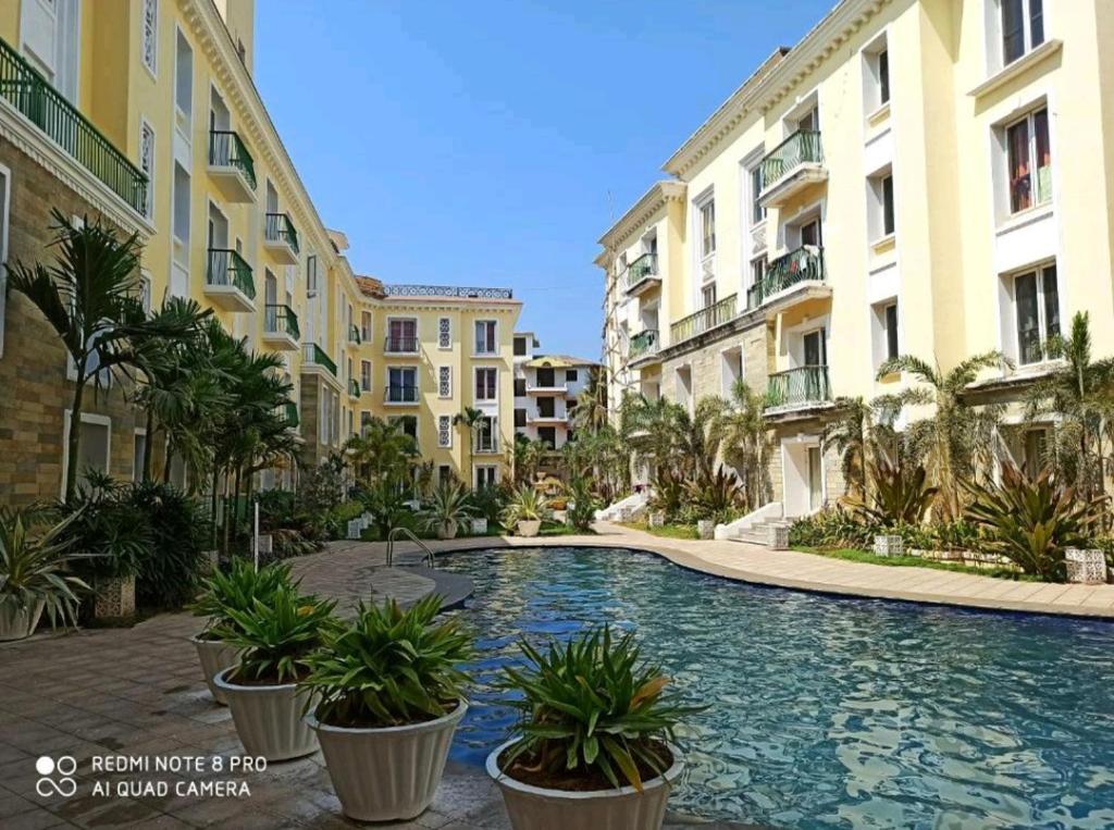 a swimming pool in the middle of some buildings at Kivi's kozy 2bhk luxurious apartment Goa by leela homes in Arpora