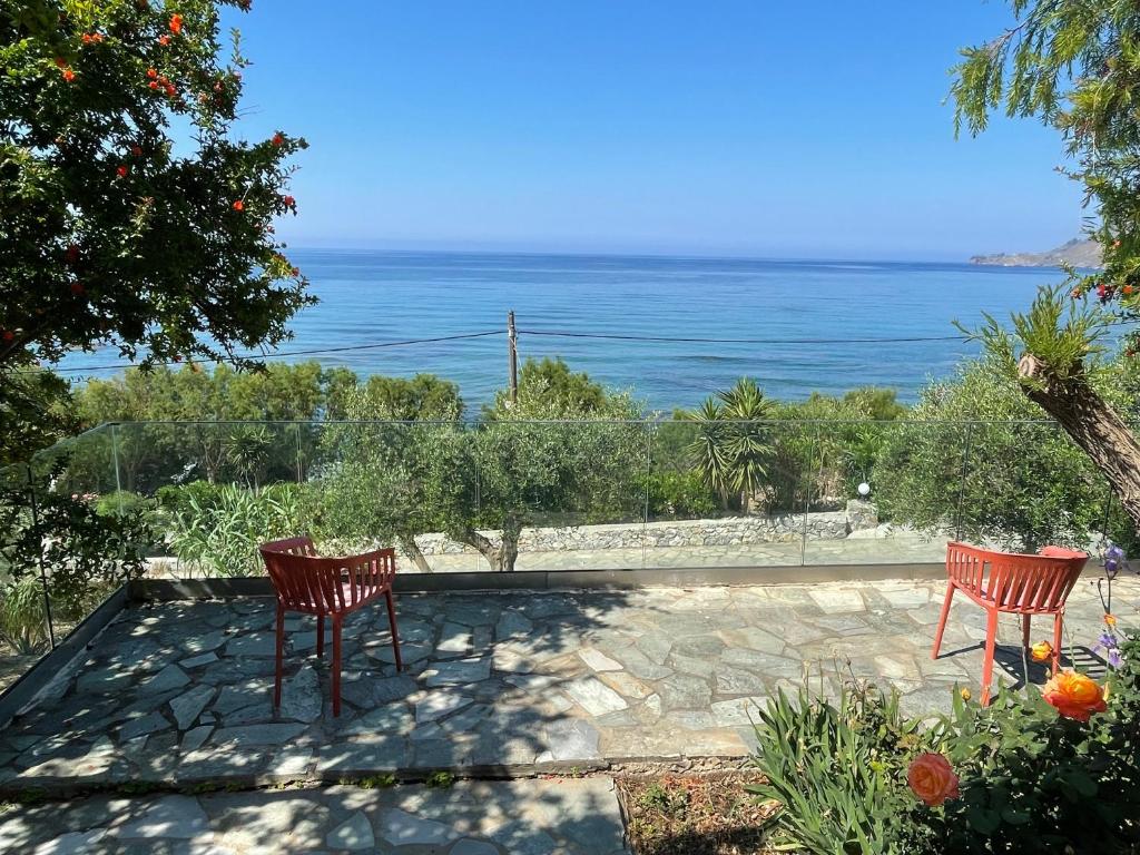 two red chairs sitting on a patio overlooking the ocean at Horizon Beach Hotel in Plakias
