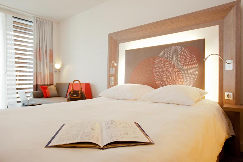 a bedroom with a bed with an open book on it at Novotel Paris 17 in Paris