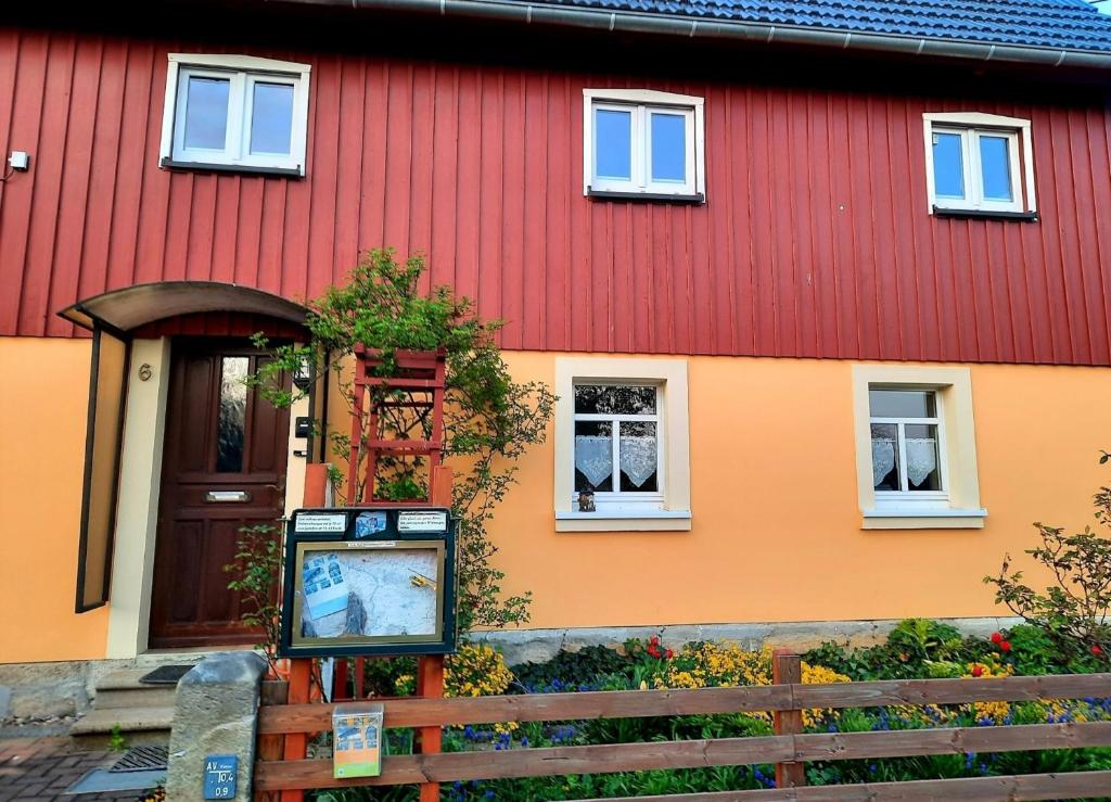 um edifício vermelho e laranja com um sinal em frente em FeWo Dorn OG Haus Sandsteinliebe em Sebnitz