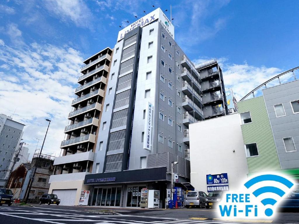 a tall white building on a city street at HOTEL LiVEMAX Himeji Ekimae in Himeji