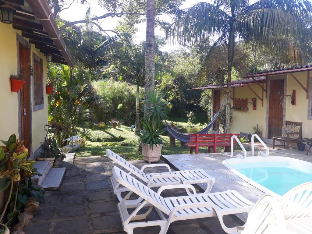 un patio con sillas y una hamaca junto a una casa en Sítio e Pousada Recanto Dos Ipês, en Teresópolis