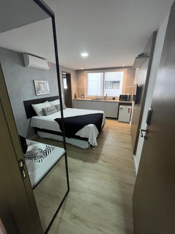 Cet appartement comprend une chambre avec un miroir, un lit et une cuisine. dans l'établissement Flat 313 Bauten Cabo Branco, à João Pessoa