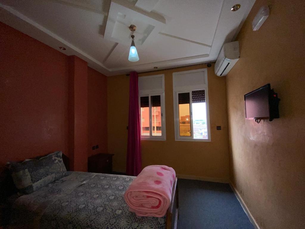 Un dormitorio con una cama con una sábana rosa. en Hotel Achokre, en Oulad Yaïch