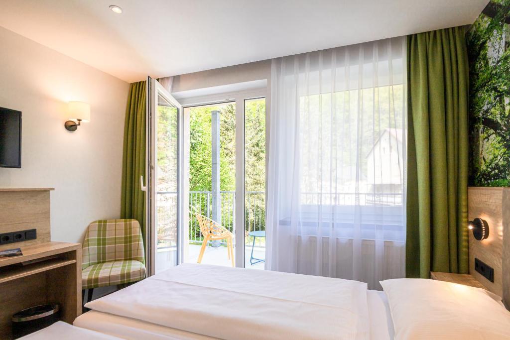 ein Hotelzimmer mit einem Bett und einem Balkon in der Unterkunft Hotel garni Grundmühle in Bad Schandau