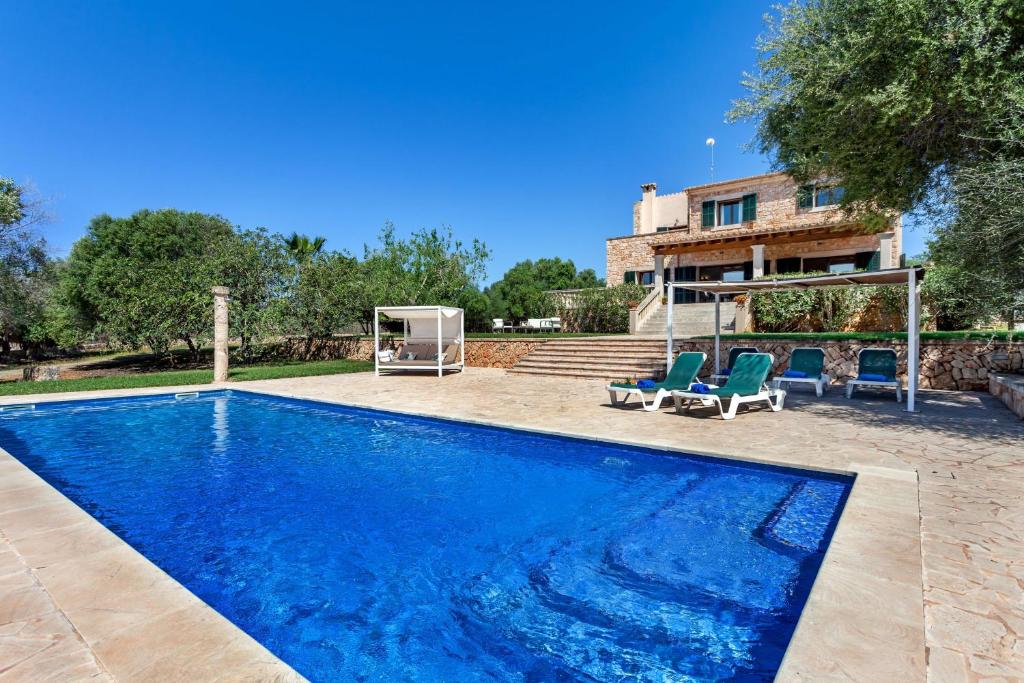 a swimming pool with two chairs and a house at Bassa Seca mit Pool und Wifi in Santanyi