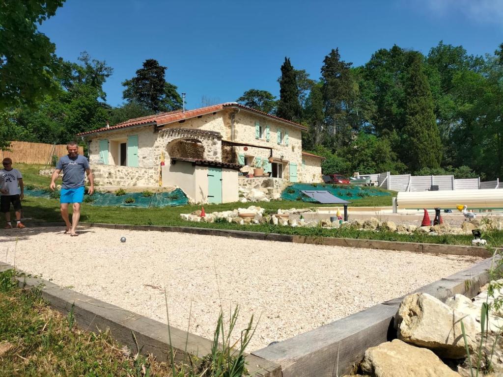 Um homem está de pé em frente a uma casa. em Gîte Le Malartic Gersois avec piscine em Montaut-les-Crénaux