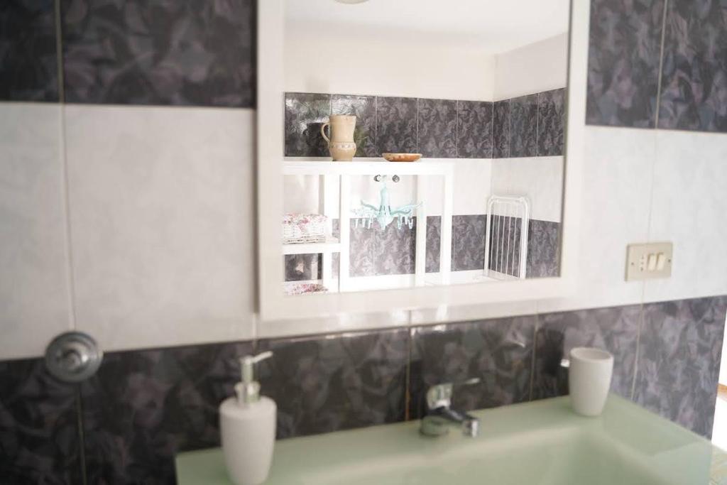 ein Badezimmer mit einem Waschbecken und einem Spiegel darüber in der Unterkunft Il trullo di Mattia in Noci