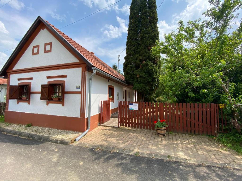 ein kleines weißes Haus mit einem Holzzaun in der Unterkunft Hétmérföldes Vendégház in Szaknyér
