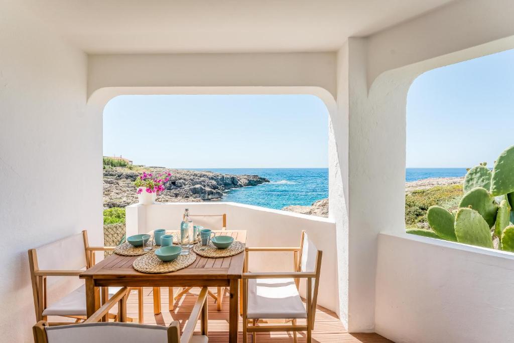 jadalnia ze stołem i krzesłami oraz widokiem na ocean w obiekcie Binibeca Sunset w mieście Sant Lluis