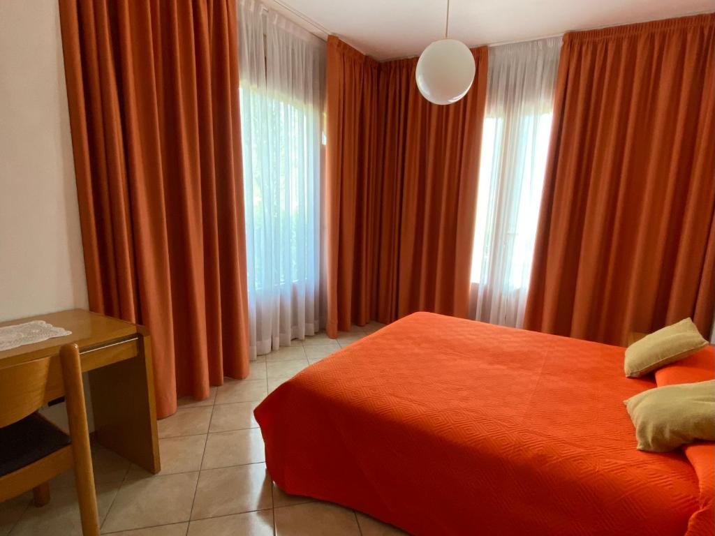 a bedroom with orange curtains and a bed and a table at Villa Gianna in Limone sul Garda