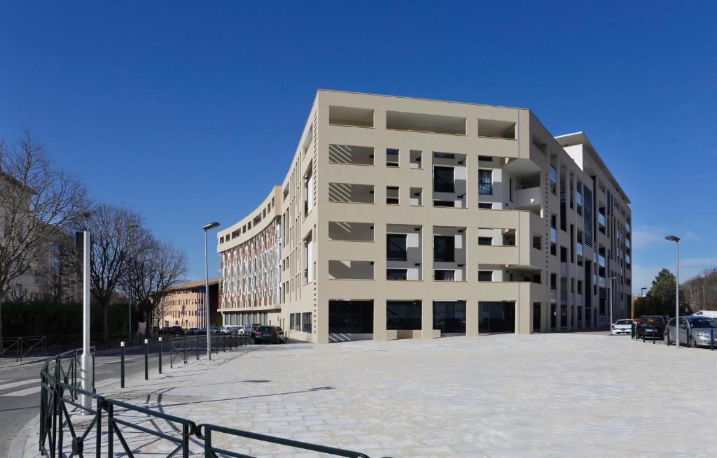 a large white building in a parking lot at Résidence Néméa Aix Campus 1 in Aix-en-Provence