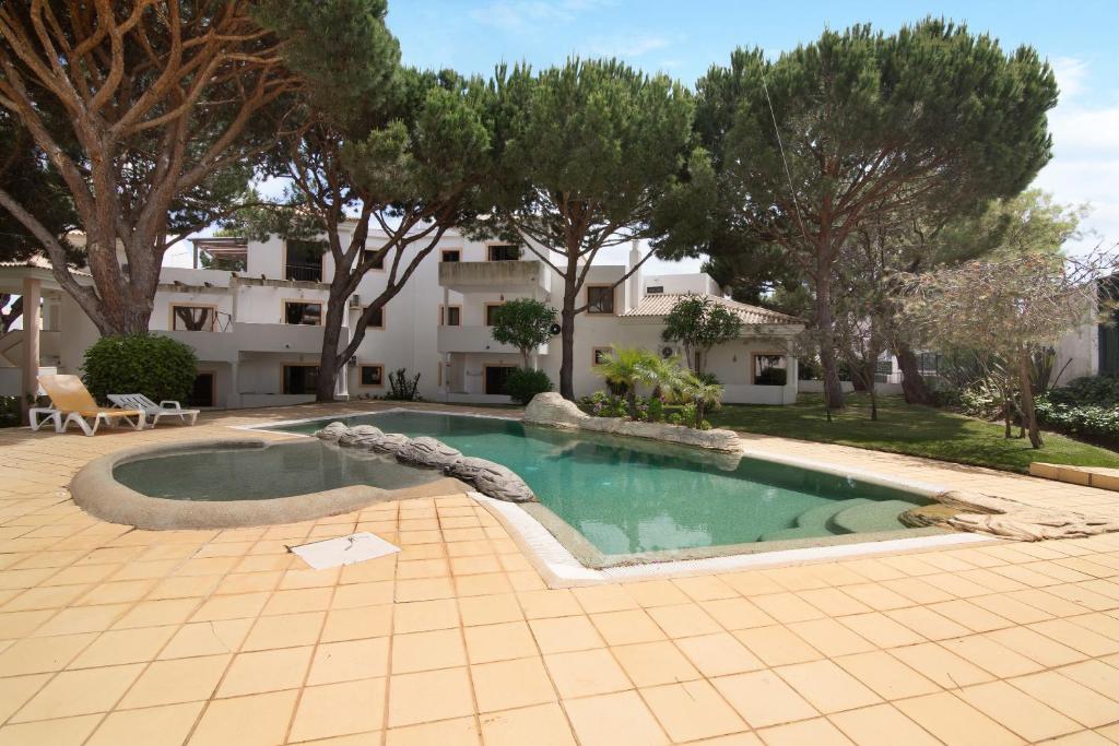 uma piscina em frente a um edifício com árvores em Apartamento Jardins da Falésia em Albufeira