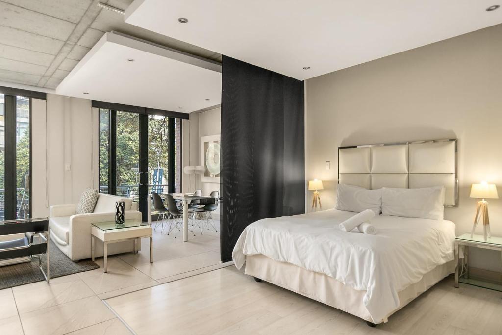 a bedroom with a large bed and a living room at Melrose Arch Luxury Apartment - WITH GENERATOR in Johannesburg