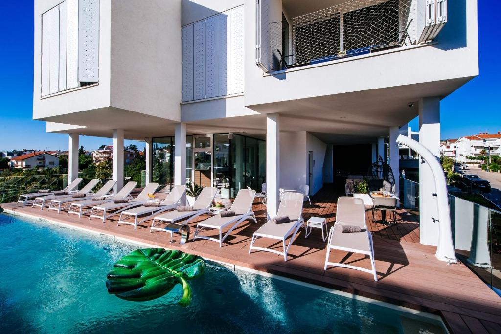 a resort with a pool and chairs and a building at Dedaj Resort - Villa Auri in Zadar