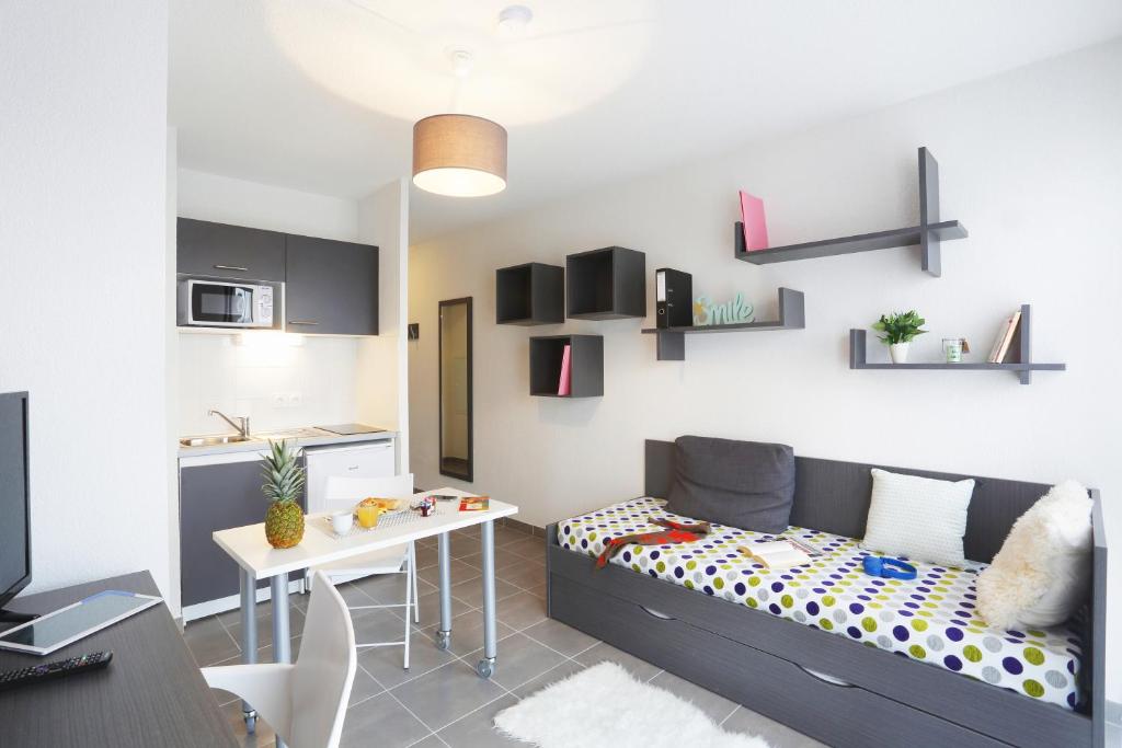 un salon avec un lit et une table dans l'établissement Résidence Nemea Aix Campus 2, à Aix-en-Provence