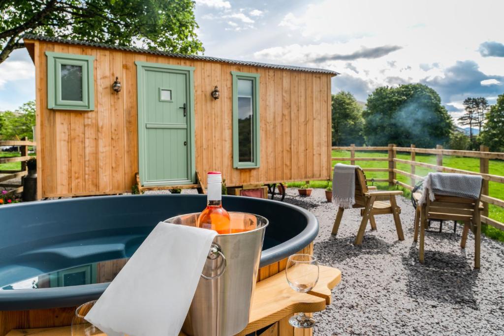 Una botella de vino en un cubo junto a una casita en Elephant View Shepherds Hut, en Caernarfon