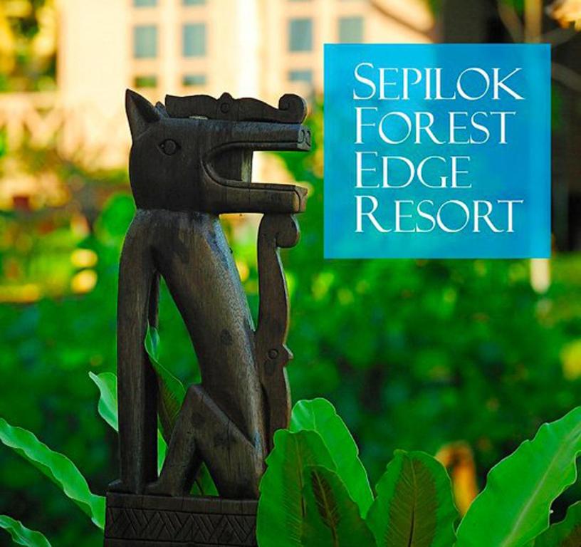 a statue of a cat sitting on a fence with a sign at Sepilok Forest Edge Resort in Sepilok