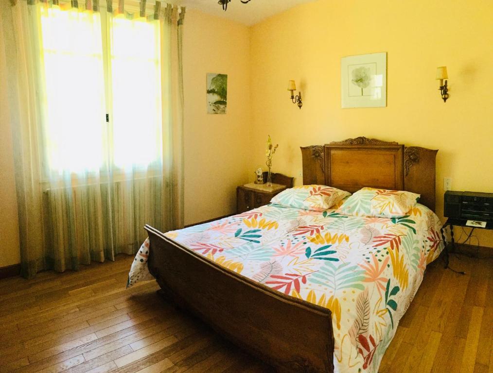 a bedroom with a large bed with a colorful comforter at Le refuge des canards in Saint-Aubin-le-Cloud