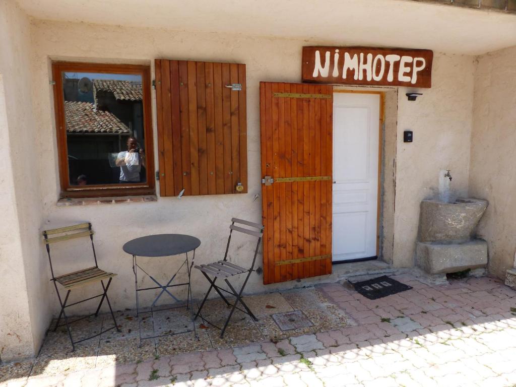 ein Gebäude mit einer Tür, einem Tisch und Stühlen in der Unterkunft le Nimhotep in Briançonnet