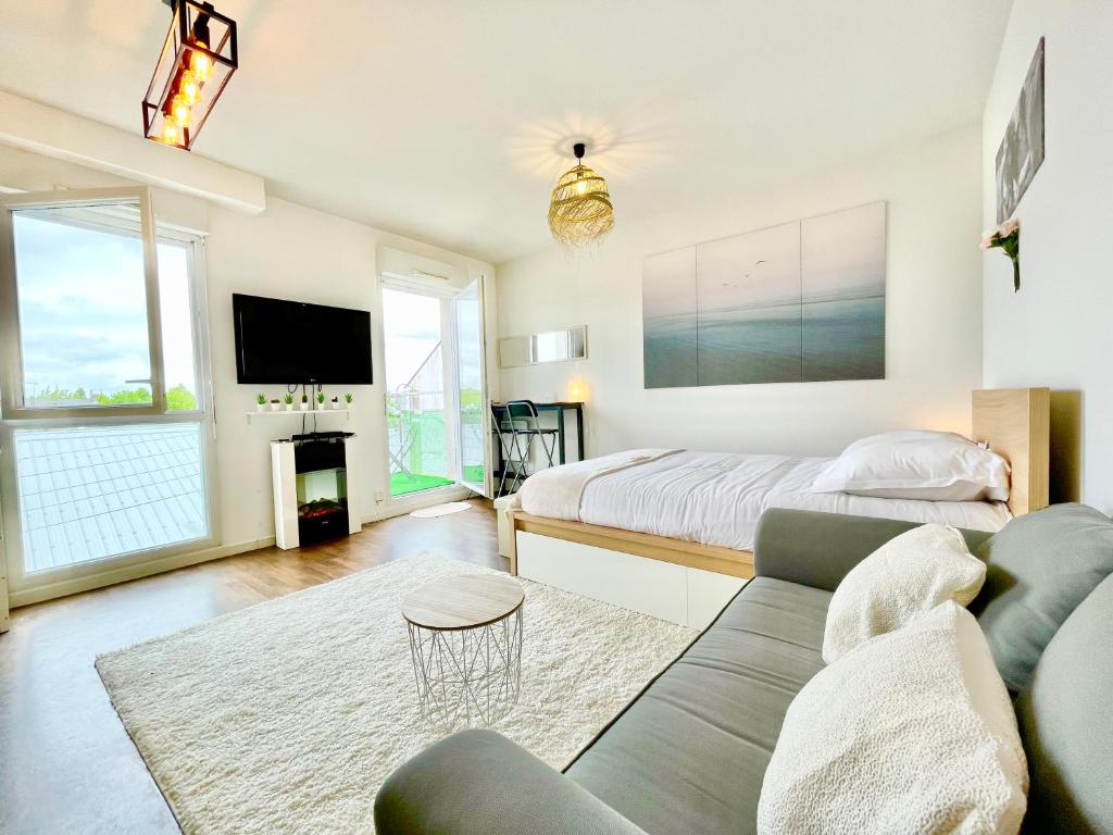 un salon avec un lit et un canapé dans l'établissement Saint Nazaire - White Lion - Centre ville - Au calme - Parking privatif aérien - Internet haut débit Fibre, à Saint-Nazaire