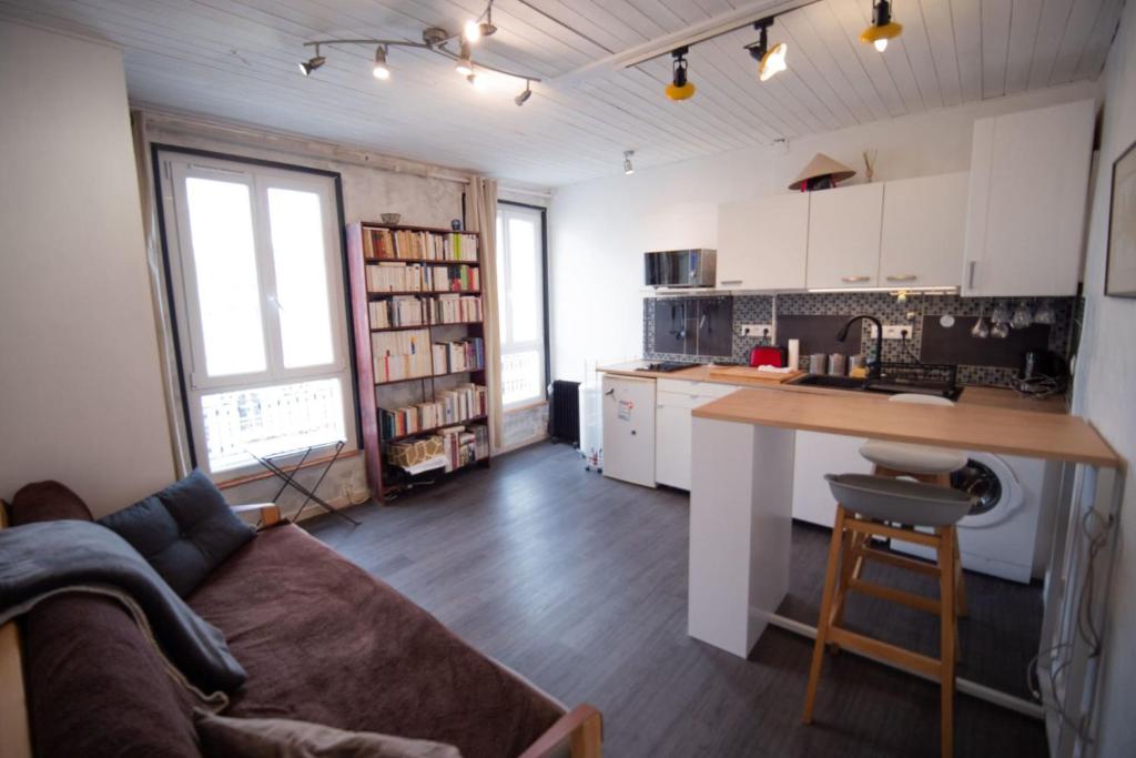un salon avec un canapé et une cuisine avec un comptoir dans l'établissement Cozy 1 Bedroom Apartment In 14th, à Paris