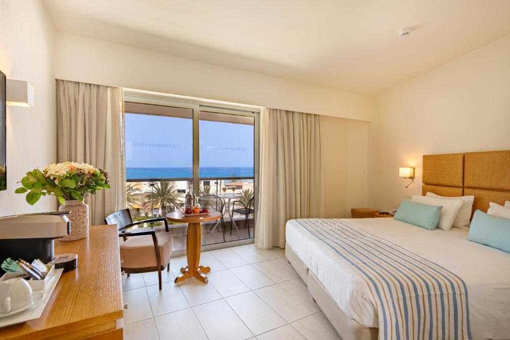 a hotel room with a bed and a view of the ocean at Minos Hotel in Rethymno