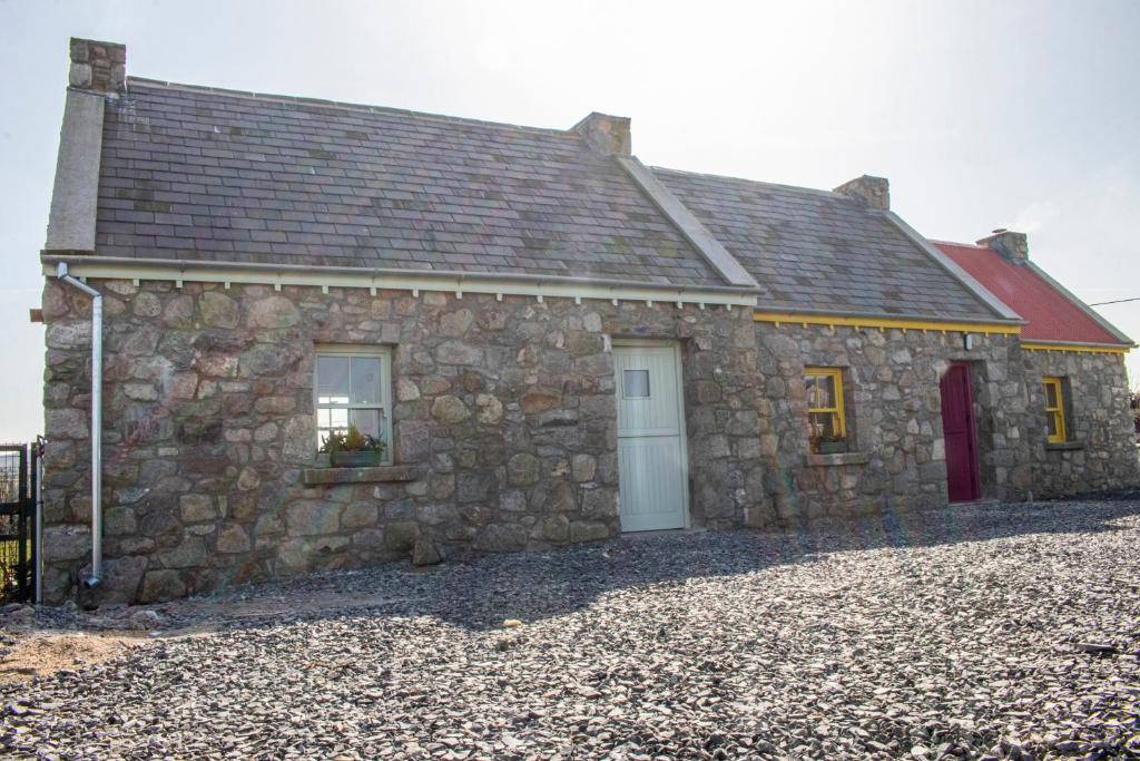 a stone house with a white door and a red roof at Slieve Gullion Getaways in Meigh