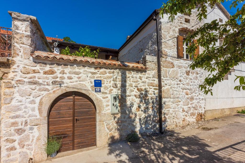 um edifício de pedra com uma porta de garagem de madeira em STARA KUĆA - old stone house em Grižane