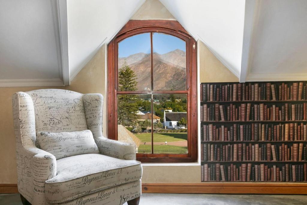 Habitación con silla y ventana con libros. en J's Audacious Living Montagu Self Catering, en Montagu