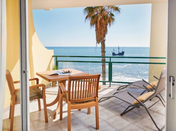 balcone con tavolo, sedie e vista sull'oceano di Lovely apartment with pool and sea view a Funchal