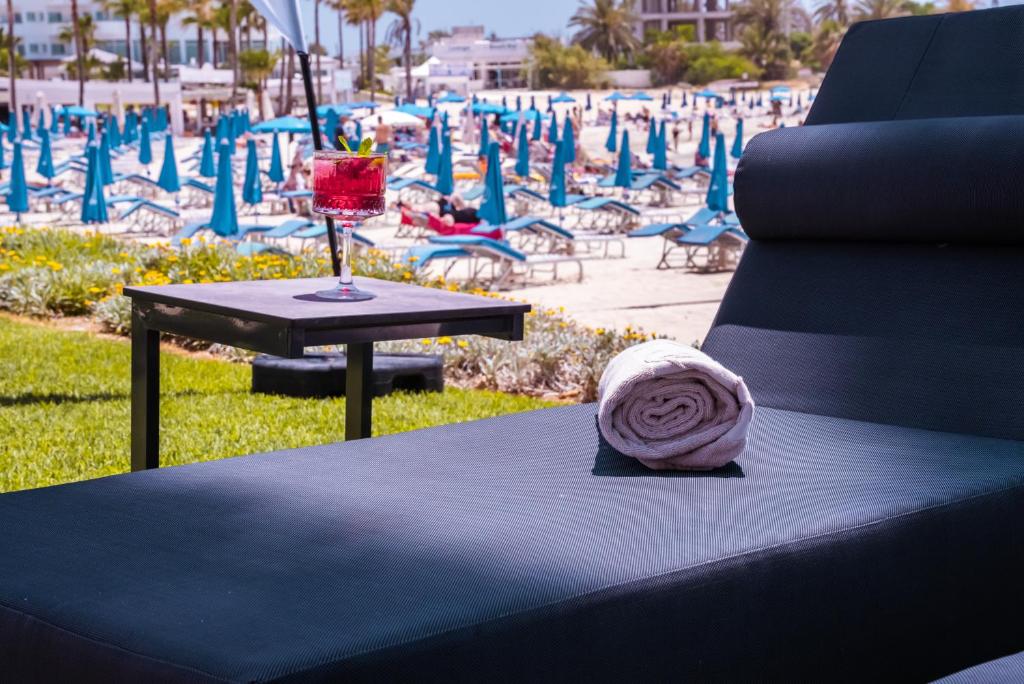 a table with a drink on it next to a beach at Pavlo Napa Beach Hotel in Ayia Napa