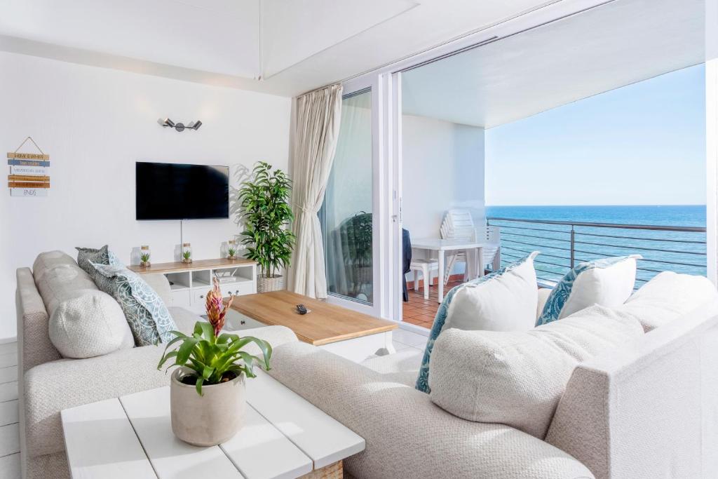 a living room with white furniture and a large window at Ocean Blue at Chakas Cove, Beachfront Apartment in Ballito