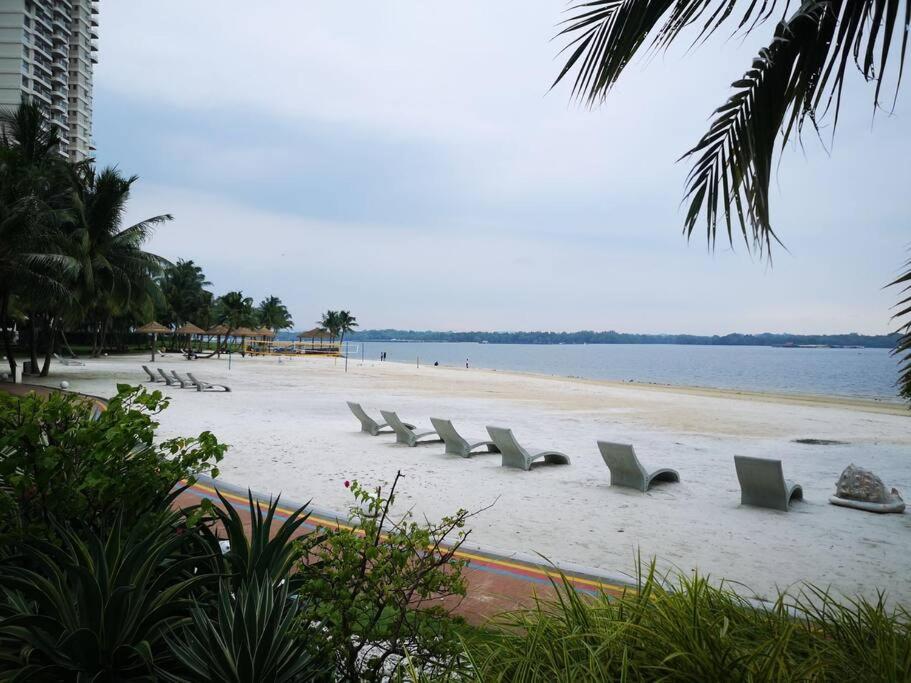 uma fila de cadeiras numa praia perto da água em Country Garden Bay Point Homestay By Easyhomestay em Johor Bahru