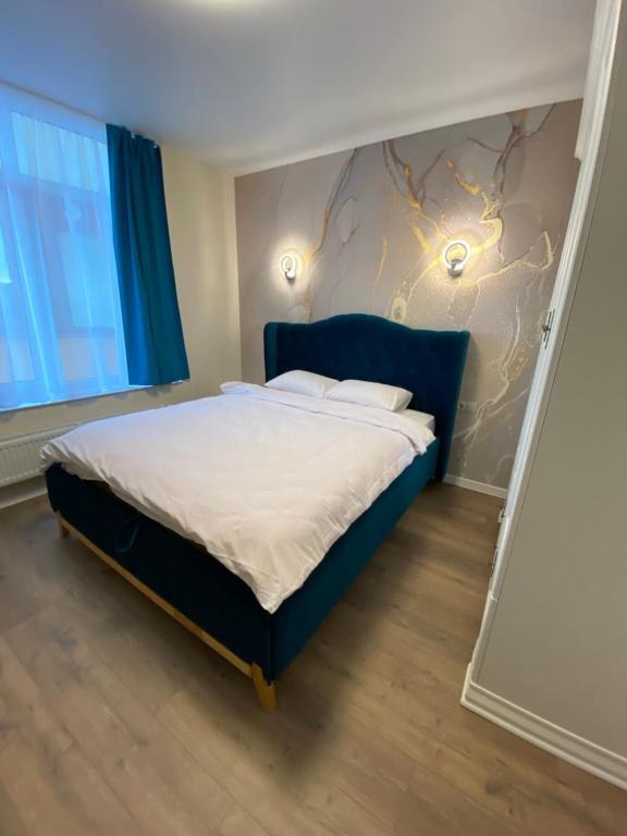 Schlafzimmer mit einem großen Bett mit blauem Kopfteil in der Unterkunft Нові апартаменти на Роксолани16 in Truskawez
