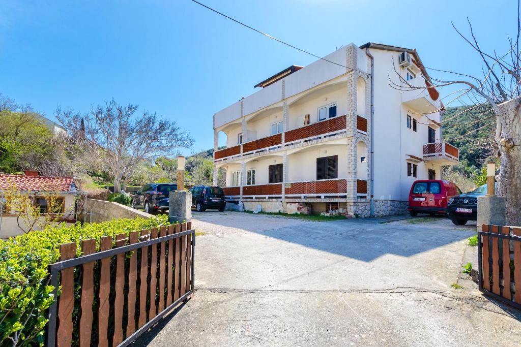 a white building with a fence in front of it at Apartments Luka in Supetarska Draga