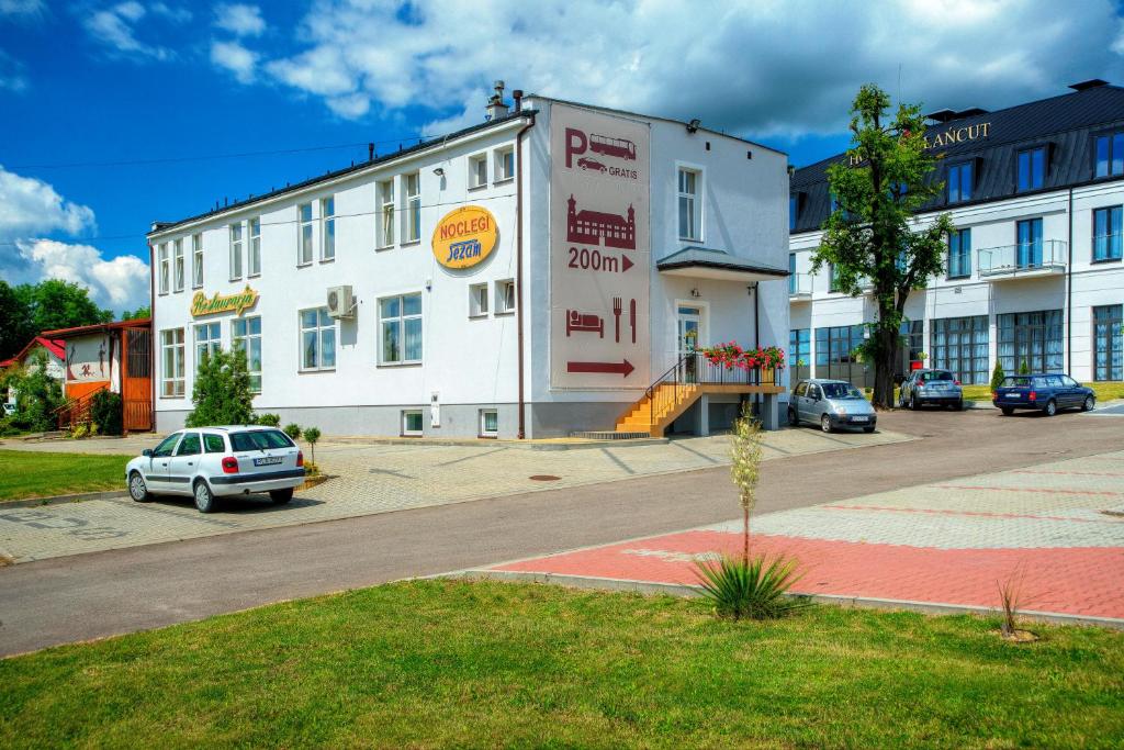 a white building with a car parked in front of it at Noclegi Sezam in Łańcut