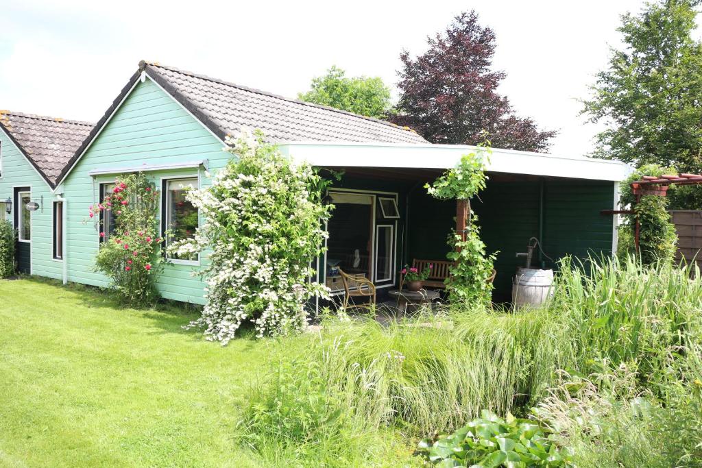 een groen huis met een veranda en een tuin bij perelaar in Langelille