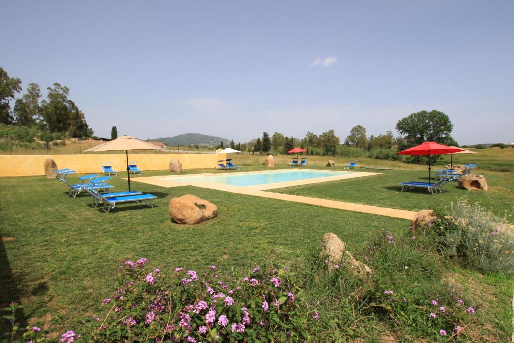 Agriturismo Piperedda في Irgoli: مسبح فيه كراسي ومظلات في الميدان